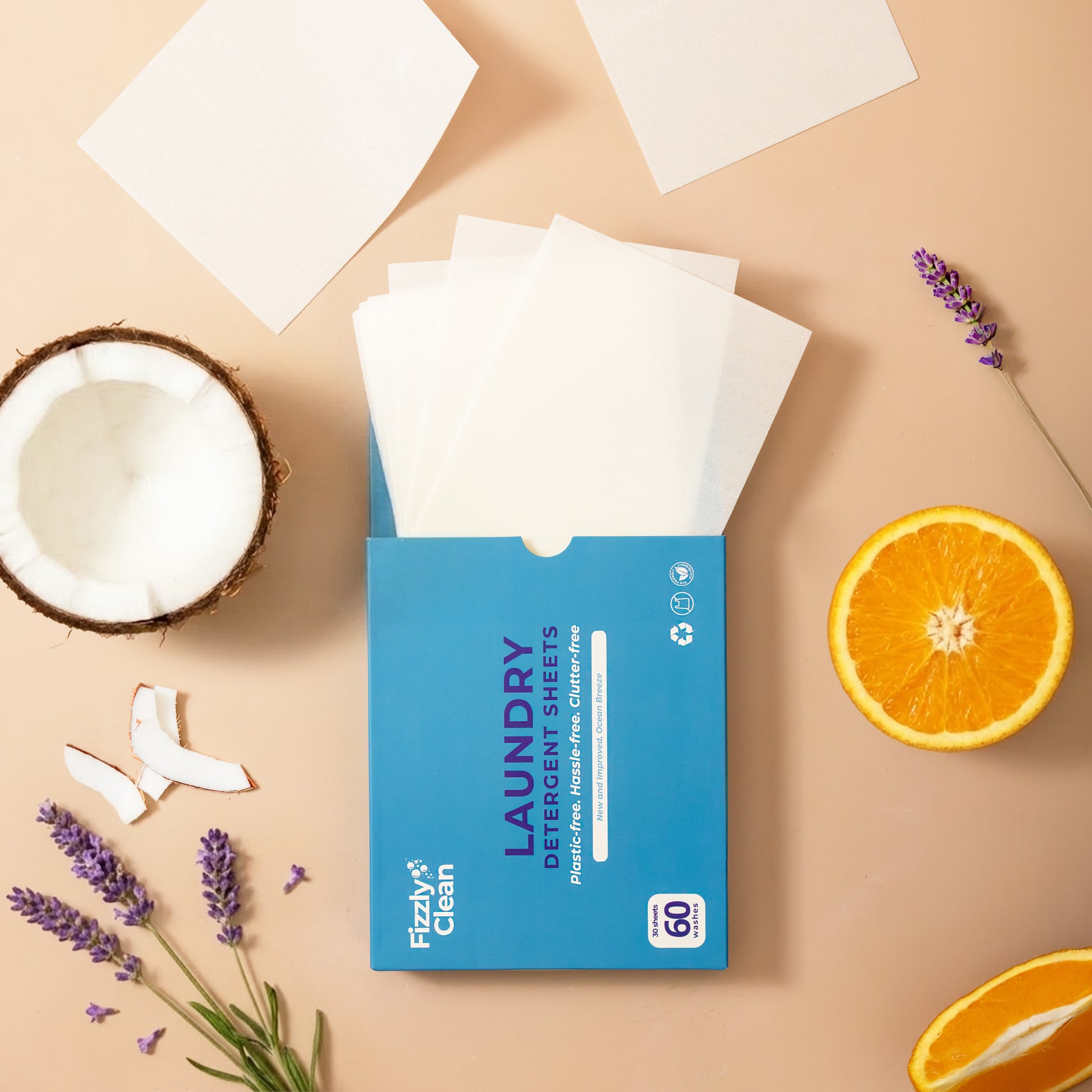Box of Fizzy Clean laundry detergent sheets on a beige background with coconut, orange, and lavender.