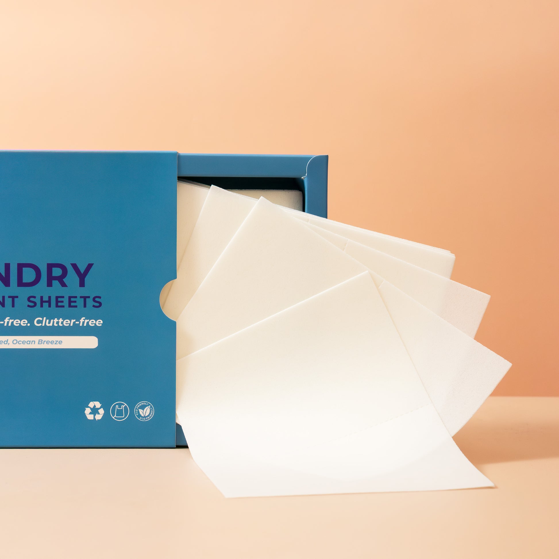 Laundry Detergent sheets spilling out of a blue box on a beige background