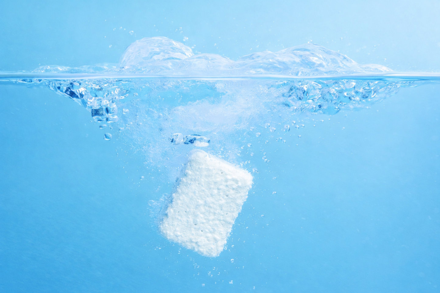 Fizzly clean tablet dissolving in water with bubbles on a blue background