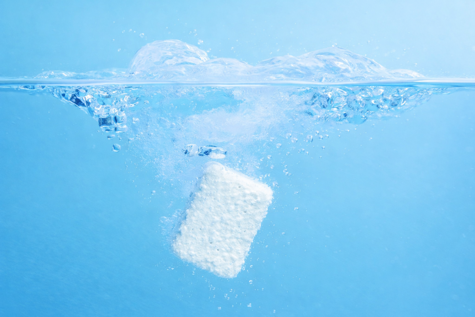 Fizzly clean tablet dissolving in water with bubbles on a blue background