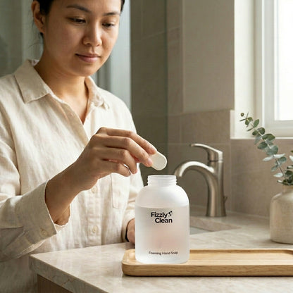Person using a bottle labeled 'Fizzyly Clean' in a bathroom setting.