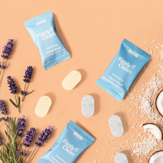 Fizzy Clean foaming hand wash tablets on a peach background with lavender and coconut elements.